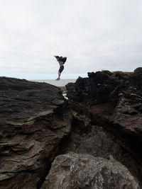 Man standing on rock against sky