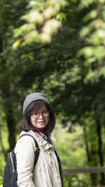 Portrait of woman standing against trees