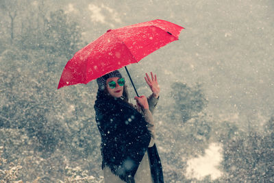 Woman with umbrella standing in snow