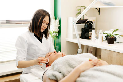 A cosmetologist performs a skin cleansing procedure in a cosmetology room, wipes his face 