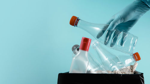 Person holding bottle against blue background