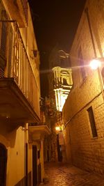 Low angle view of illuminated street amidst buildings at night