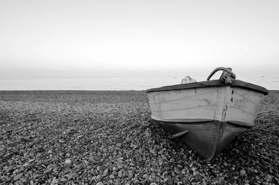 Boat moored on beach against sky