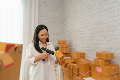 Happy businesswoman smiling while using bar code reader on box in office