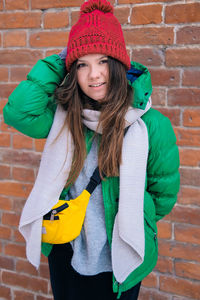 Portrait of smiling woman standing against brick wall