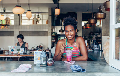 Portrait of smiling young woman having drink in restaurant