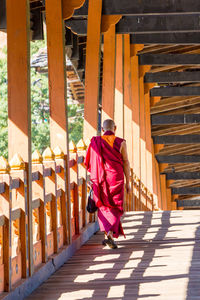 Rear view of monk walking on covered bridge