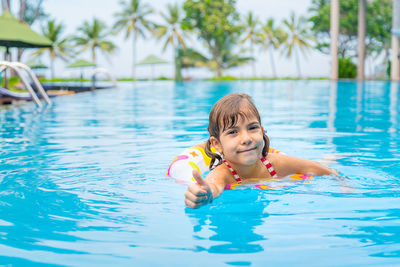 Girl gesturing thumbs in swimming pool