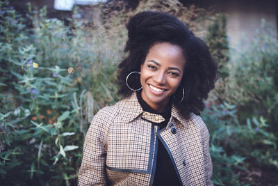 Beautiful african american young woman with afro and large hoop earrings in a stylish coat