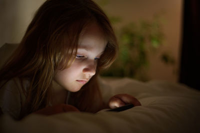 Close-up portrait of a serious young woman relaxing on bed at home