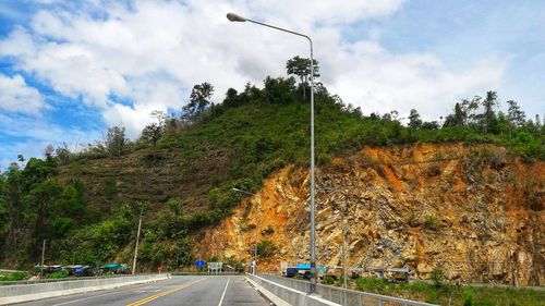 Road by trees against sky