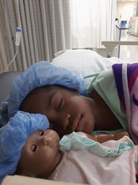 Girl with doll sleeping on bed in hospital