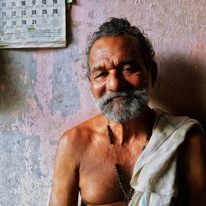 Portrait of shirtless man against wall