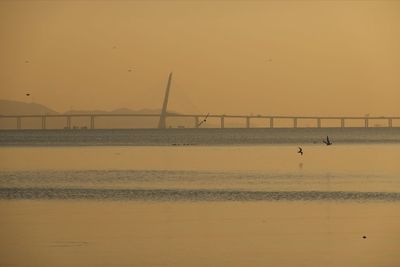 View of bridge over sea against orange sky