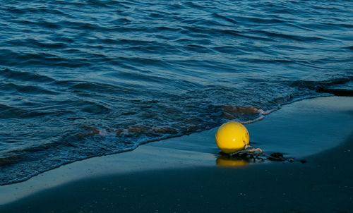 High angle view of yellow floating buoy on the shore and clean blue sea