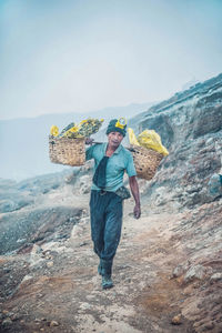 Full length of man standing on rock against sky