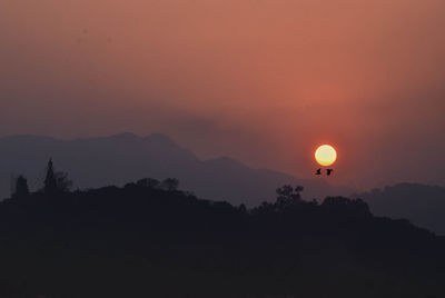 Scenic view of silhouette mountains against orange sky