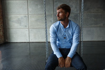 Young man sitting against wall