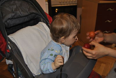 Cropped hands of showing eggs to son on baby stroller at home