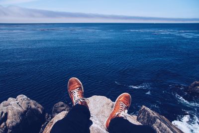 Low section of man on beach against sky