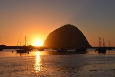 Boats in sea against sky during sunset