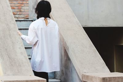 Rear view of woman standing against wall