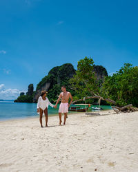 People at beach against blue sky