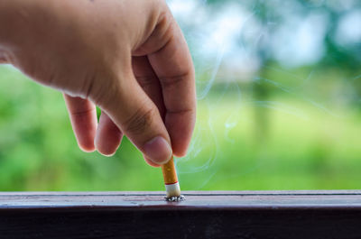 Close-up of human hand stubbing cigarette on table