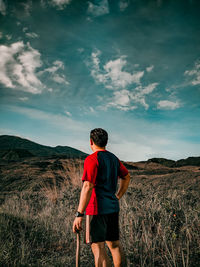 Rear view of man standing on field against sky