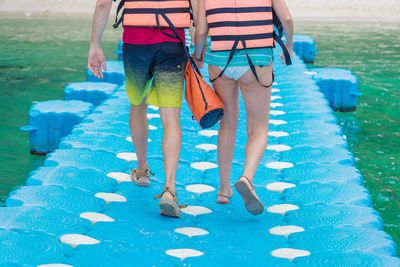 Low section of women walking by swimming pool