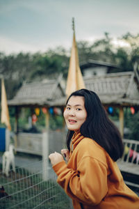 Portrait of young woman standing against building