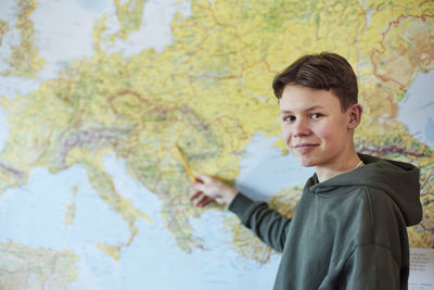 Portrait of boy pointing on map in class