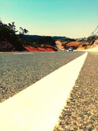 Close-up of road by trees against sky