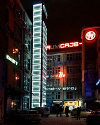 Illuminated city street and buildings against sky at night