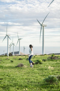 Full length of woman standing against windmill