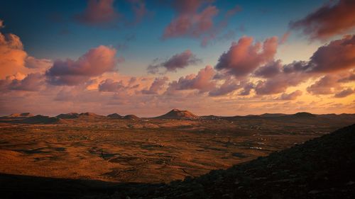 View of landscape against cloudy sky during sunset