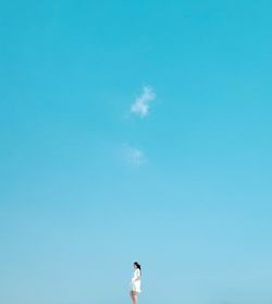 Woman standing against blue sky
