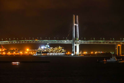 Illuminated bridge over river against sky at night