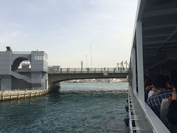 People on bridge over river in city against sky