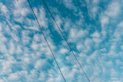 Low angle view of power lines against blue sky