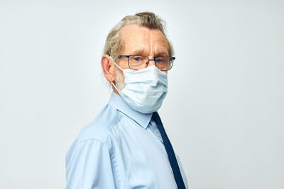 Portrait of woman wearing surgical mask against white background
