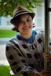 Portrait of a young girl wearing a fedora at the door