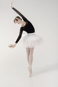 A ballerina in a bodysuit and tutu poses in motion showing ballet elements while standing on pointes