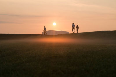 Silhouette people jogging against sky during sunset