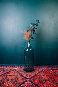 Flower vase on carpet against wall