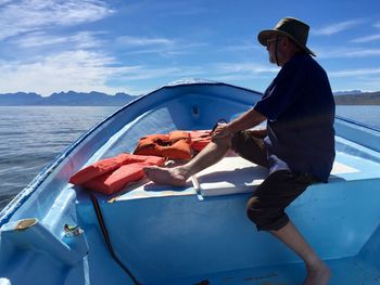 Side view of men on boat in sea against sky