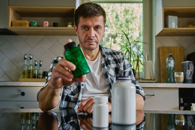 Portrait of young man drinking water while sitting at home