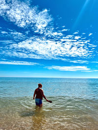 Rear view of woman in sea against sky