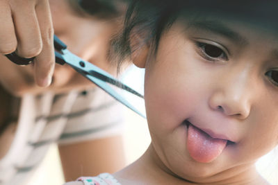 Close-up of woman cutting hair for girl