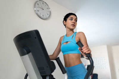 Young woman training at the gym using eliptical crosstrainer